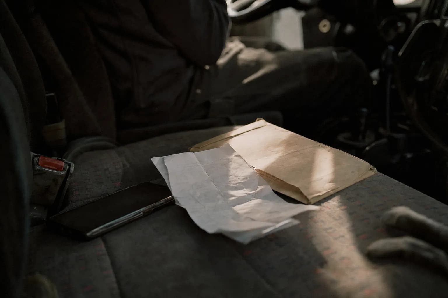 A crumpled work ticket and an envelope on a truck seat