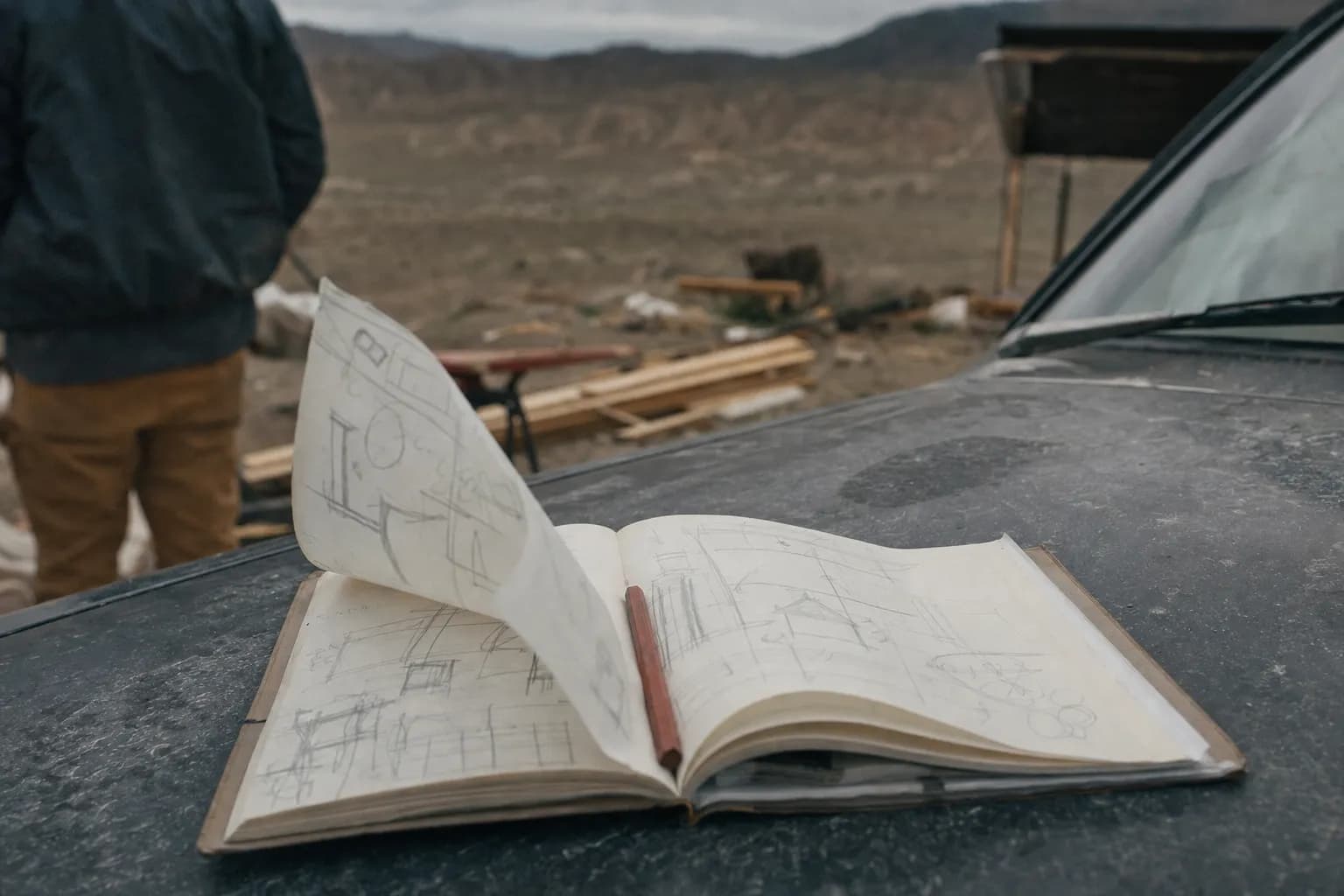 A field notebook open on the hood of a dusty truck